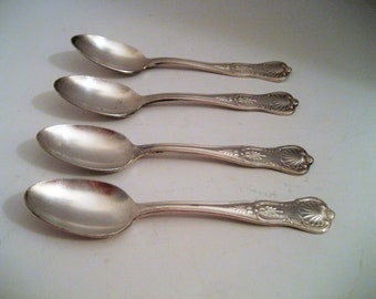 May include: Four silver teaspoons with ornate handles. The spoons are arranged in a row, with the handles pointing to the right.