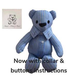 May include: A blue and white striped teddy bear with a collar and buttons. The bear is sitting down with its arms outstretched. The text "Annie's Memory Bears" is visible in the background.