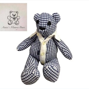 May include: A blue and white checkered teddy bear wearing a white button-down shirt. The bear is sitting with its legs crossed and has a black embroidered nose and eyes. The bear is labeled "Annie's Memory Bears".