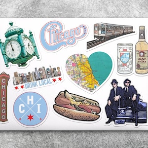May include: A collection of Chicago-themed stickers featuring a clock tower, a skyline, a map of the city, a hot dog, a train, a can of soda, a bottle of liquor, and two men in suits standing on a car. The stickers are on a white laptop.