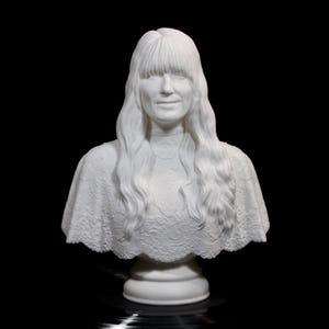 May include: A white bust sculpture of a person with long, wavy hair and bangs. The sculpture features a detailed lace-like pattern on the shoulders and a round base. The bust is set against a black background.