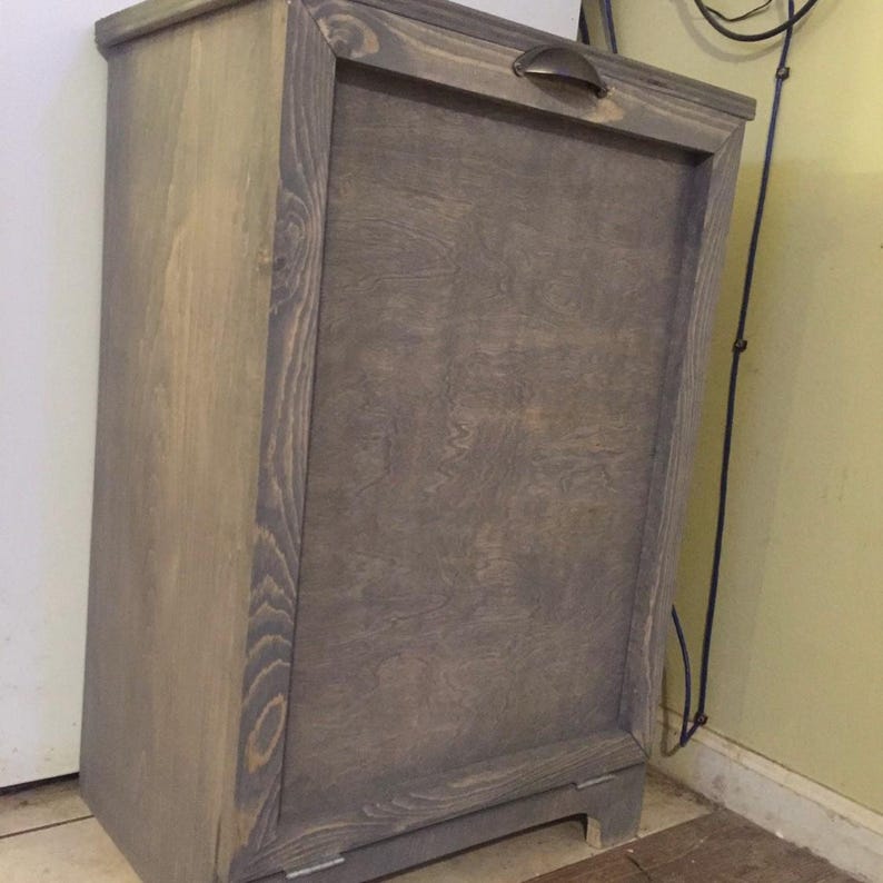 May include: A grey wooden cabinet with a single door and a metal handle. The cabinet has a rustic, farmhouse style.