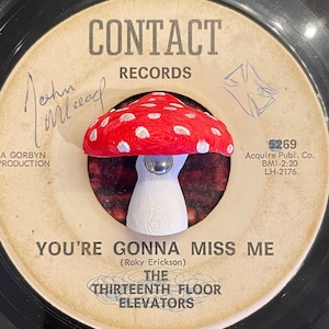 Könnte beinhalten: Ein rot-weißes pilzförmiges Objekt befindet sich auf einer Vintage-Vinyl-Schallplatte. Das Etikett der Schallplatte zeigt "CONTACT RECORDS" und "YOU'RE GONNA MISS ME" von The Thirteenth Floor Elevators. Der Pilz hat einen weißen Stiel.
