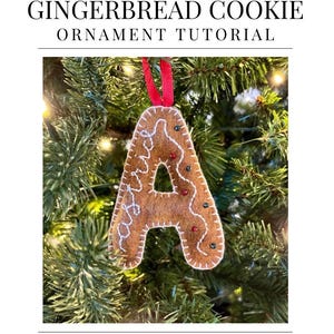 Puede incluir: Adorno de fieltro con la letra "A" en forma de galleta de jengibre, con costuras blancas y adornos rojos, verdes y marrones, colgado de una cinta roja en un árbol de Navidad. El texto "FELT LETTER GINGERBREAD COOKIE ORNAMENT TUTORIAL" está en la parte superior.