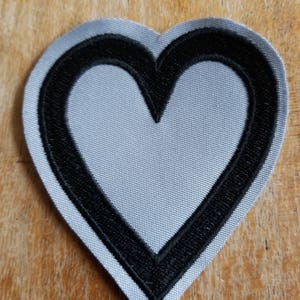 May include: A gray heart-shaped patch with a black outline.