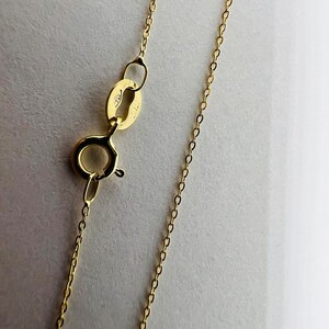 May include: A gold chain necklace with a lobster clasp fastening. The chain is made of small, round links.