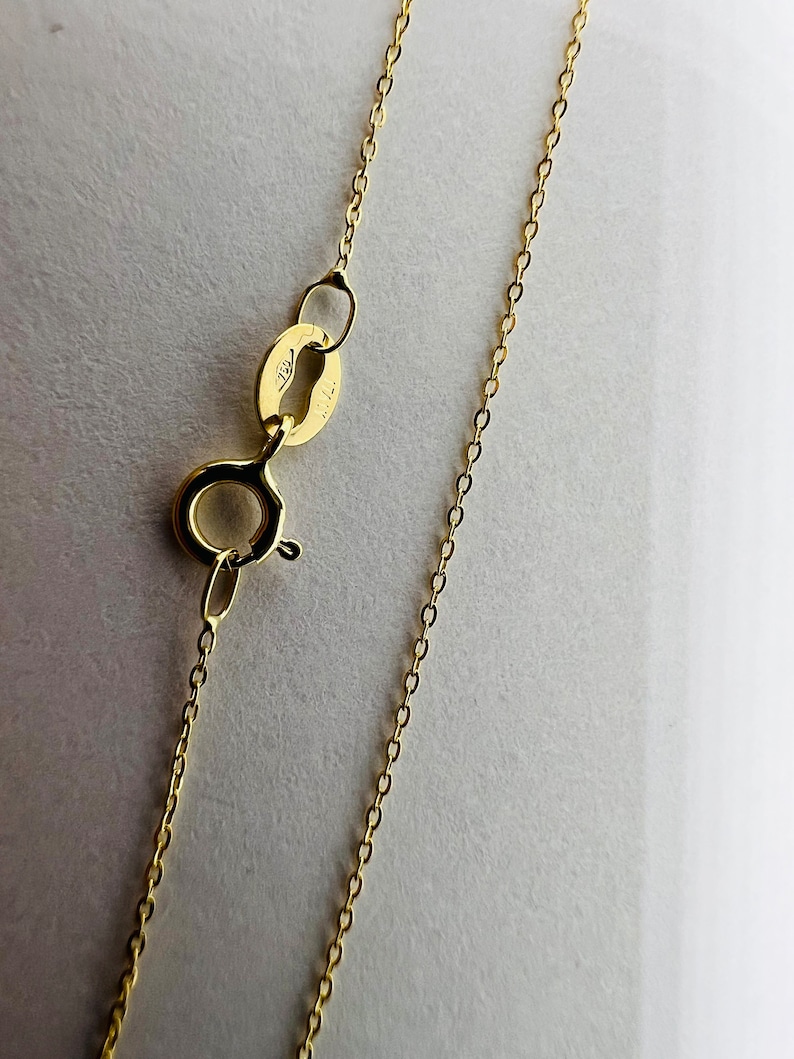 May include: A gold chain necklace with a lobster clasp fastening. The chain is made of small, round links.