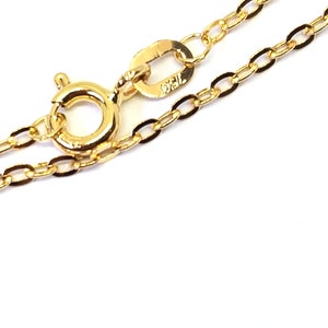 May include: Close-up of a delicate gold necklace with an oval link chain. The necklace features a lobster clasp and a small tag with the marking "750". The chain is displayed against a white background.