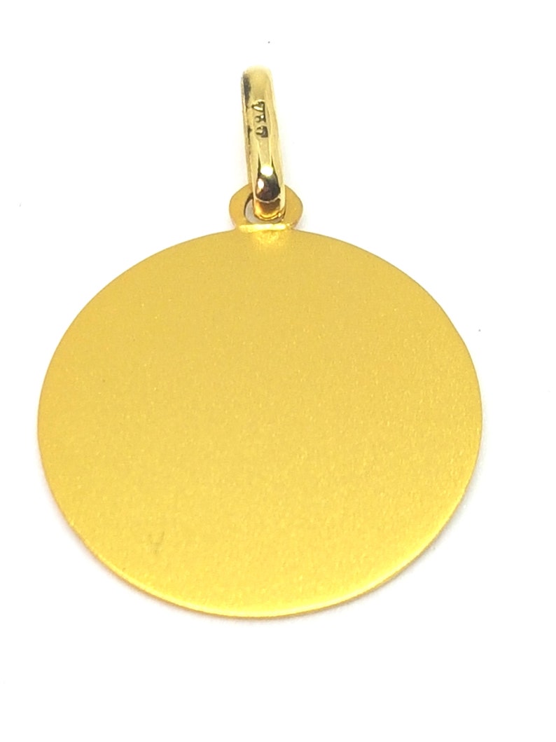 Puede incluir: Un colgante dorado con un dise&ntilde;o circular. El colgante tiene una superficie texturizada y un peque&ntilde;o lazo en la parte superior para una cadena. El lazo tiene marcas. El colgante est&aacute; sobre un fondo blanco.