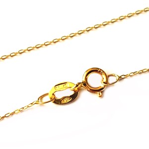 May include: A gold chain necklace with a lobster clasp fastening. The chain is made of small, oval-shaped links.