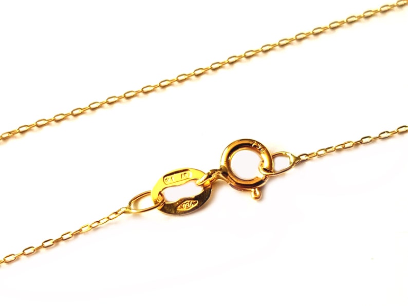 May include: A gold chain necklace with a lobster clasp fastening. The chain is made of small, oval-shaped links.
