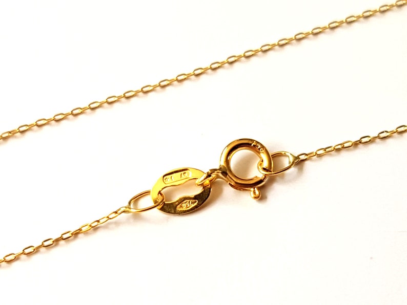 May include: A gold chain necklace with a lobster clasp closure. The clasp is marked "14K" and "585".