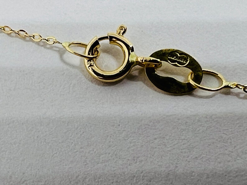 May include: Close-up of a gold chain necklace clasp with a small oval tag that says "925 Italy".