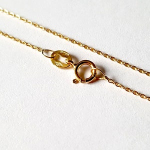 May include: A gold chain necklace with a lobster clasp fastening. The chain is made of small, oval-shaped links.