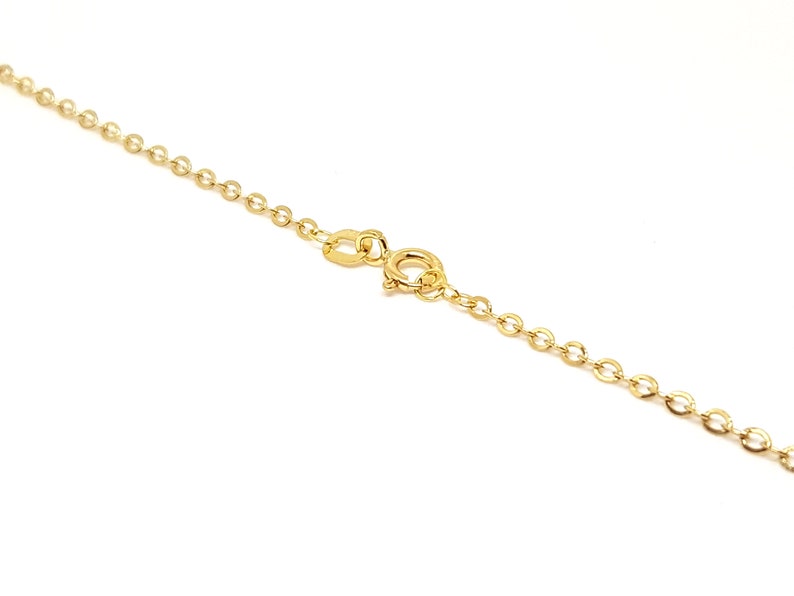 May include: A delicate gold necklace with a small oval link chain and a spring ring clasp. The necklace is set against a white background, highlighting its bright, shiny appearance. The chain is a classic design, suitable for everyday wear.