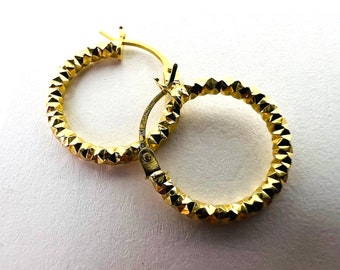 Può includere: Un paio di orecchini a cerchio dorati con un design testurizzato a forma di diamante.