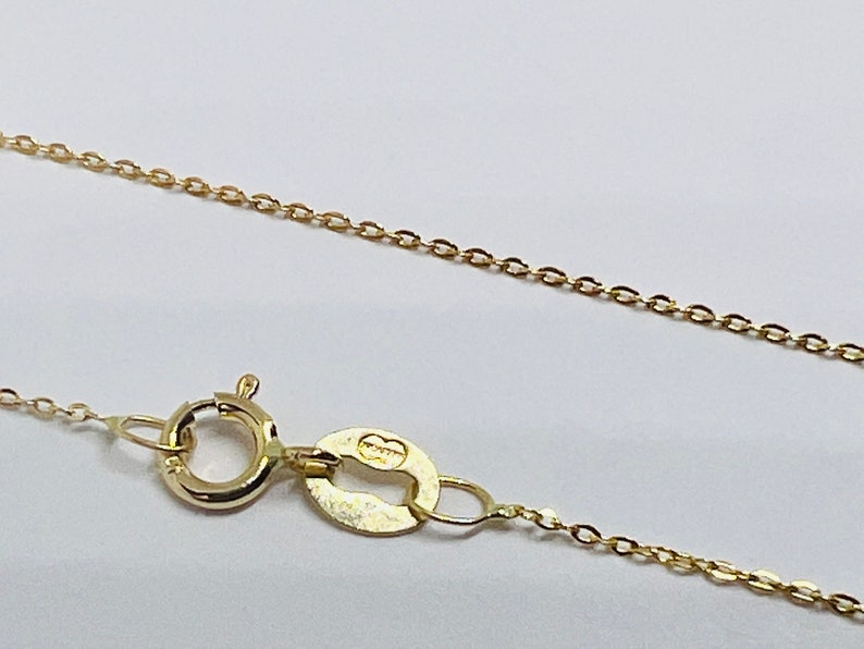 May include: A gold chain necklace with a lobster clasp and a small oval tag inscribed with the word "Italy".