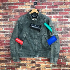 Puede incluir: Una chaqueta vaquera gris oscuro con cierre de cremallera y múltiples bolsillos. La chaqueta tiene un cuello alzado y un aspecto ligeramente desgastado.