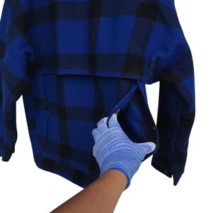 Puede incluir: Chaqueta a cuadros azul y negro con un bolsillo. La chaqueta est&aacute; hecha de un material grueso y c&aacute;lido. El bolsillo est&aacute; siendo abierto por una mano enguantada.