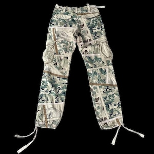 Könnte beinhalten: Beigefarbene Cargohose mit einem Tarnmuster aus verschiedenen Stoff-Patches. Die Hose hat einen Kordelzug am unteren Ende jedes Beins.