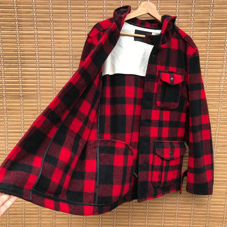 May include: Red and black plaid flannel jacket with a hood and multiple pockets. The jacket is unbuttoned and the lining is visible.
