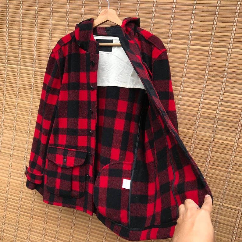 May include: Red and black plaid flannel jacket with a hood and a zipper closure. The jacket has two pockets on the front and a lined interior.