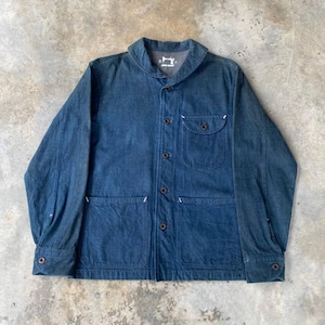 Könnte beinhalten: Blaue Jeansjacke mit klassischem Kragen, Knopfverschluss und mehreren Taschen. Die Jacke hat weiße Nahtdetails und ein kleines Logo in der Nähe des Kragens. Die Jacke ist aus mittelblauem Denim.