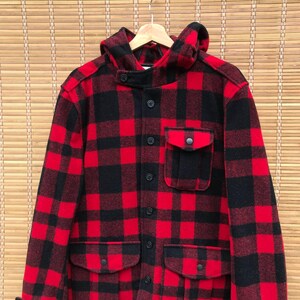 May include: A red and black plaid hooded flannel jacket with multiple pockets and button closures.