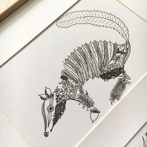 May include: A black and white line drawing of an animal, possibly a possum, made entirely of leaves and flowers. The animal is depicted in a curled up position.