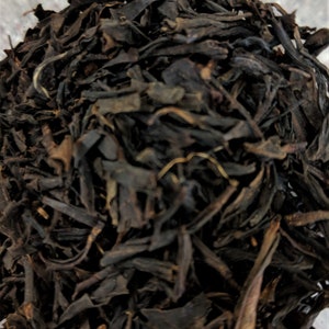 May include: Loose black tea leaves, dried and ready for brewing. The tea leaves are dark brown and have a slightly curled shape.