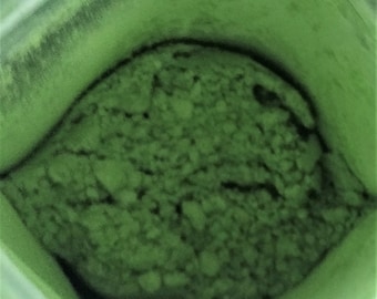 May include: A close-up of a container filled with a large amount of green powder.