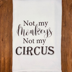 May include: White kitchen towel with black text that reads "Not my monkeys, Not my circus."