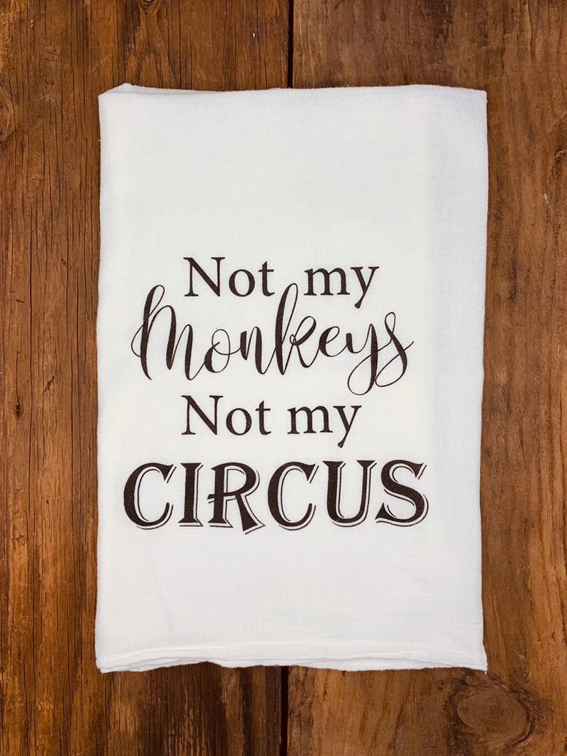 K&ouml;nnte beinhalten: Wei&szlig;es K&uuml;chentuch mit schwarzem Text, der "Not my monkeys, Not my circus." lautet.