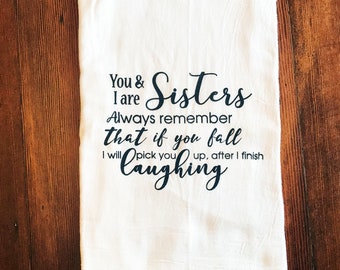 May include: White kitchen towel with black text that reads "You & I are Sisters Always remember that if you fall I will pick you up, after I finish laughing."