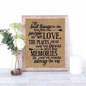 May include: A framed burlap print with a black and white quote that reads "The best things in life are the people we love, the places we've been and the memories we've made along the way."