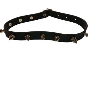 Könnte beinhalten: Schwarzer Leder-Choker mit silbernen Metallspikes.