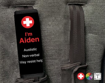May include: Black luggage strap with a red medical cross and the text "I'm Aiden" in red. The strap also has the text "Autistic, Non-verbal, May resist help" in white.