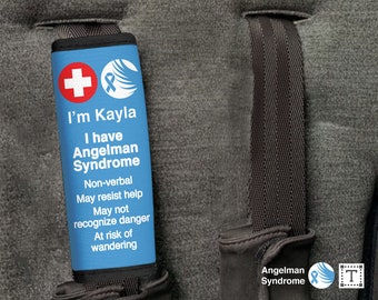 May include: Blue and black fabric strap with a white plus sign, a blue awareness ribbon, and the text "I'm Kayla I have Angelman Syndrome Non-verbal May resist help May not recognize danger At risk of wandering".