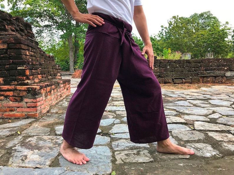 Pu&ograve; includere: Un paio di pantaloni da pescatore thailandesi di colore viola, noti anche come "pantaloni da pescatore" o "pantaloni sarong", sono realizzati in un tessuto morbido e leggero. I pantaloni sono legati in vita con una fascia e hanno una vestibilit&agrave; ampia e fluida.