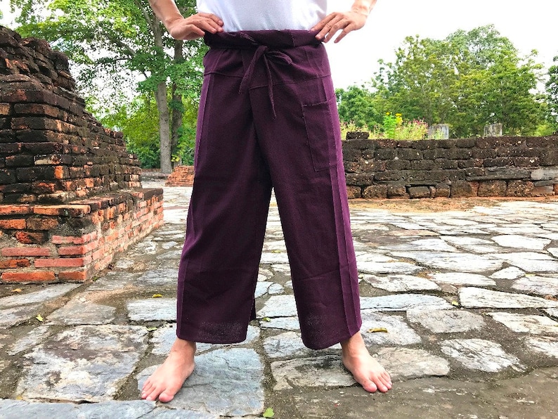 Pu&ograve; includere: Un paio di pantaloni viola con vita a coulisse e una tasca sul lato destro. I pantaloni sono realizzati in un tessuto morbido e confortevole, perfetti per rilassarsi o allenarsi.