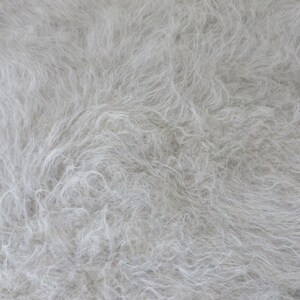 May include: A close-up of a white fluffy texture, resembling fur or a soft fabric.