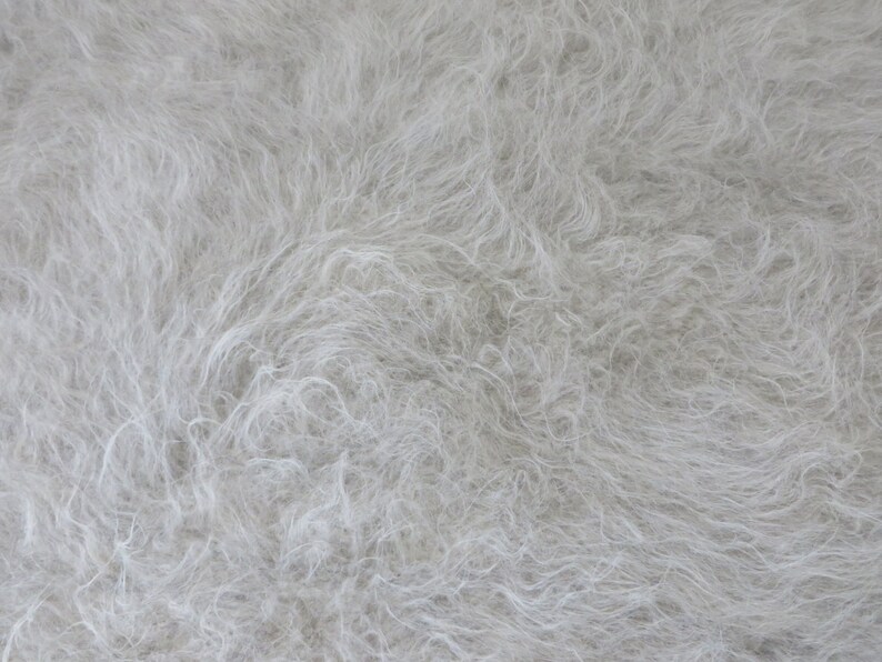 May include: A close-up of a white fluffy texture, resembling fur or a soft fabric.