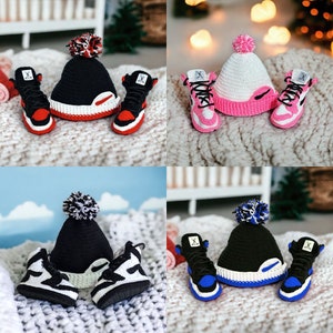 Peut inclure: Quatre ensembles de chaussures et de bonnets pour bébé en crochet. Chaque ensemble présente une combinaison de couleurs différente : noir et blanc, rose et blanc, rouge et blanc, et bleu et blanc.