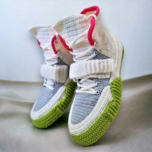 Pode incluir: Um par de t&ecirc;nis de croch&ecirc; com detalhes em branco, cinza e verde. Os t&ecirc;nis t&ecirc;m um design de cano alto e uma al&ccedil;a de velcro.