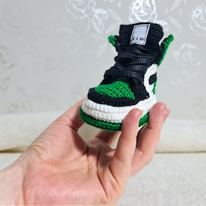 Op de afbeelding: Groene en zwarte gebreide sneaker met een witte zool en het woord "AIR" aan de zijkant.