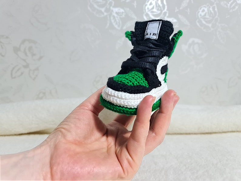 Op de afbeelding: Groene en zwarte gebreide sneaker met een witte zool en het woord "AIR" aan de zijkant.