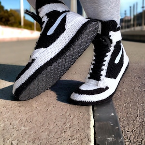 May include: A pair of black and white crocheted high-top trainers with a black rubber sole.