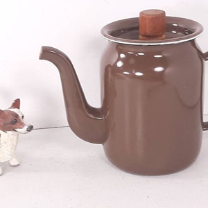 May include: A brown enamel coffee pot with a wooden lid and a white rim. The pot has a spout and a handle.