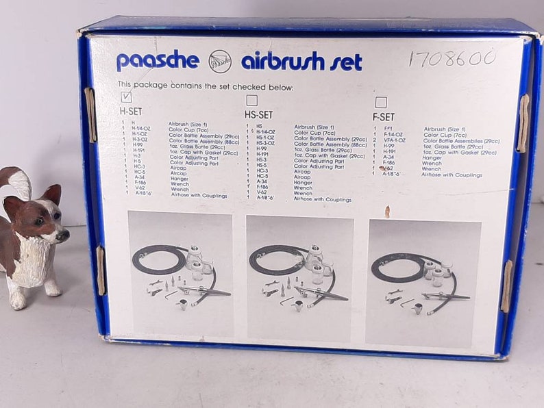 Peut inclure: Une bo&icirc;te bleue et blanche avec le texte "paasche airbrush set" et le num&eacute;ro "1708600". La bo&icirc;te contient une liste des articles inclus dans l'ensemble, y compris un a&eacute;rographe, des gobelets &agrave; peinture, des flacons de peinture et d'autres accessoires.