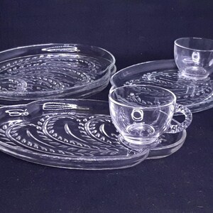 May include: Set of four clear glass serving dishes with a wheat design. The dishes are oval shaped and have a raised edge.